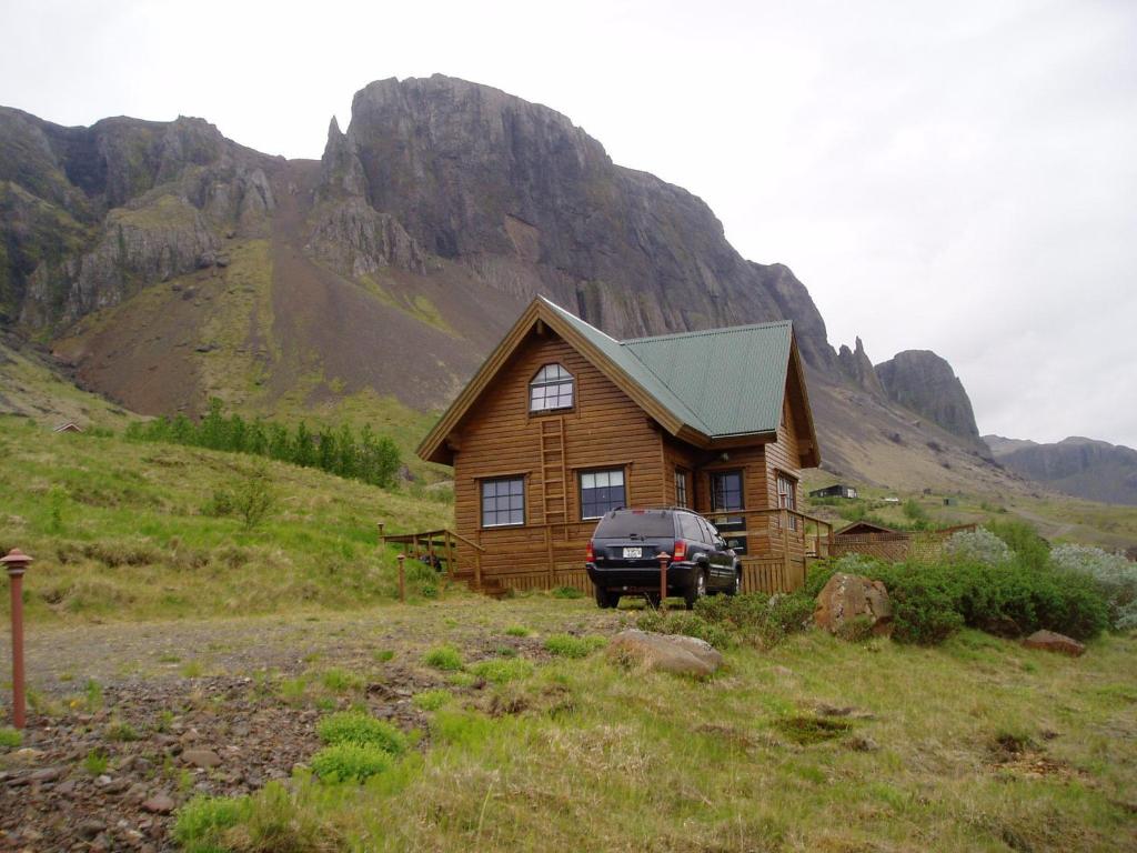 una casa de madera con un coche aparcado delante de ella en Vindheimar Cottage - Great View - Hot Tub, en Skeljabrekka