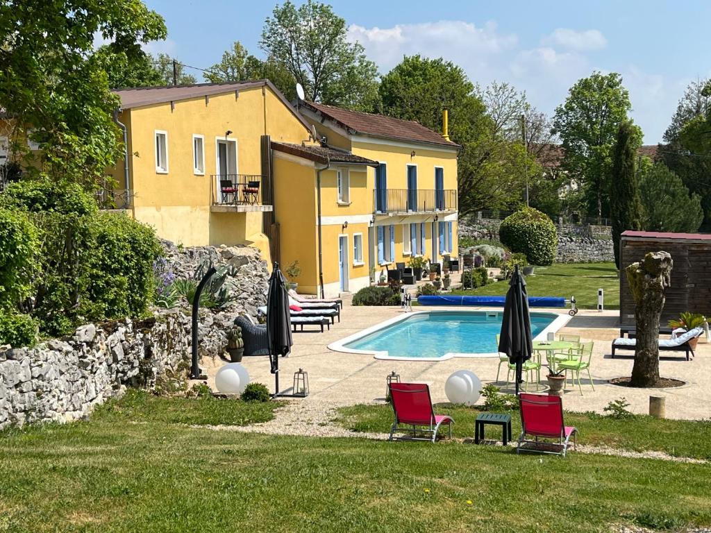 una casa y una piscina con sillas y sombrillas en Chenevières d'en Haut, en Grimault
