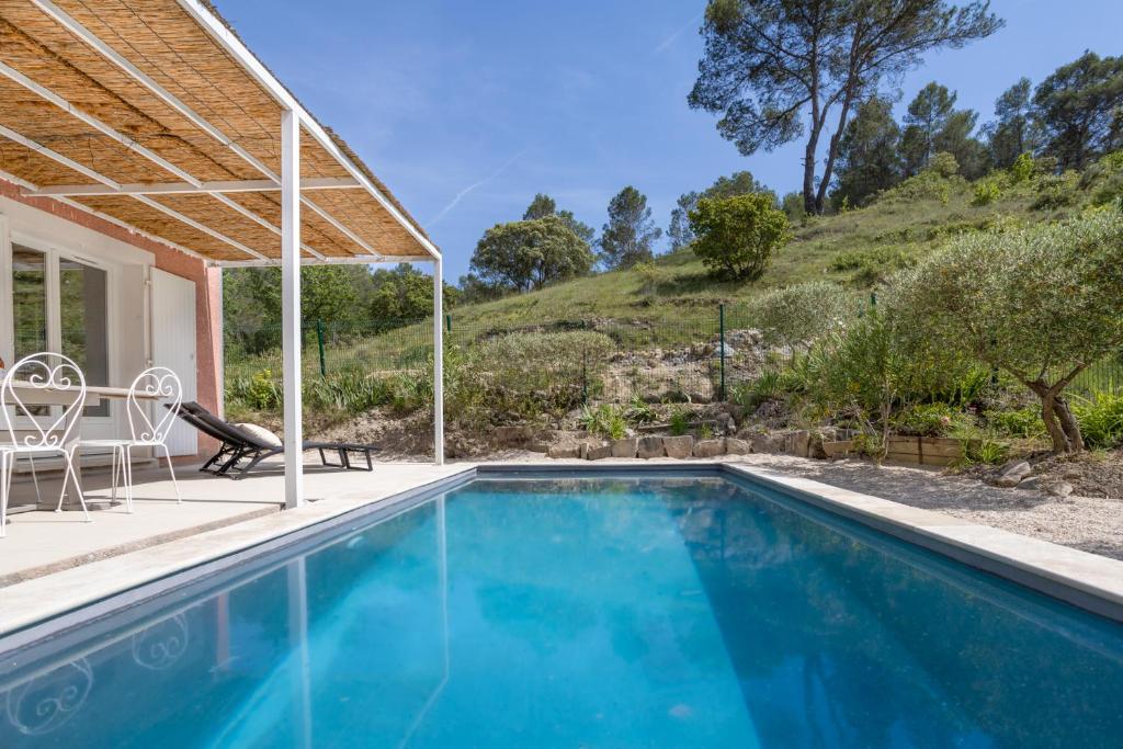 a swimming pool with a table and chairs next to a house at Petit Paradis Garrigue in Moulézan