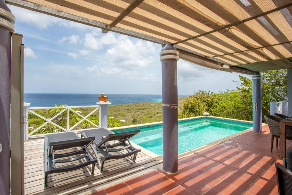 a patio with chairs and a swimming pool at Villa Coral Breeze in Willemstad