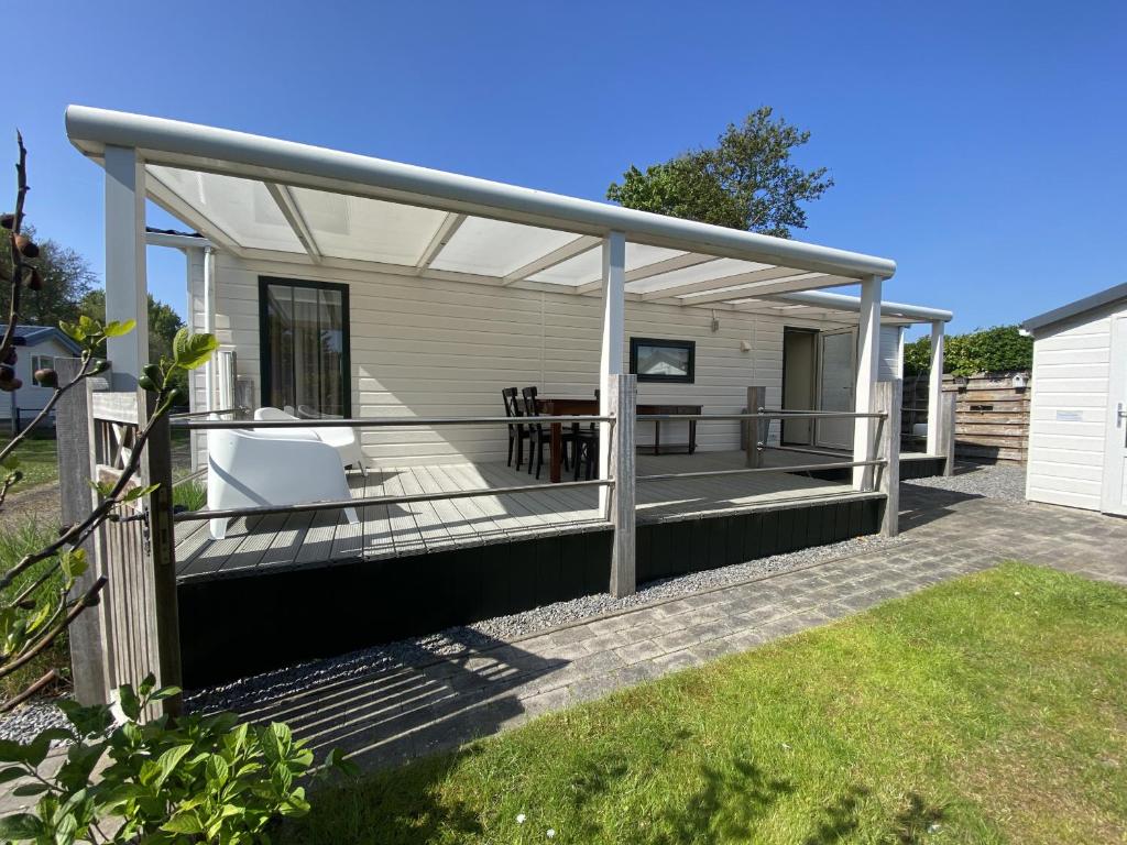 a covered deck of a house with a table and chairs at Beach Resort Kamperland - 1653 in Kamperland