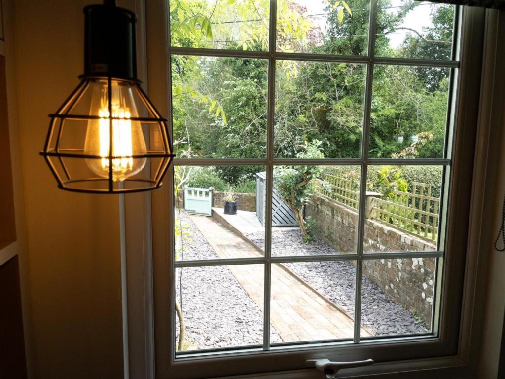 a window with a view of a garden seen through it at Redlands Cottage Surrey Hills in Dorking