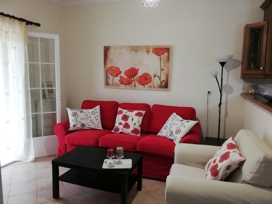 un sofá rojo en una sala de estar con mesa en Sunny stay furnished apartment in Kanoni, en Kanoni