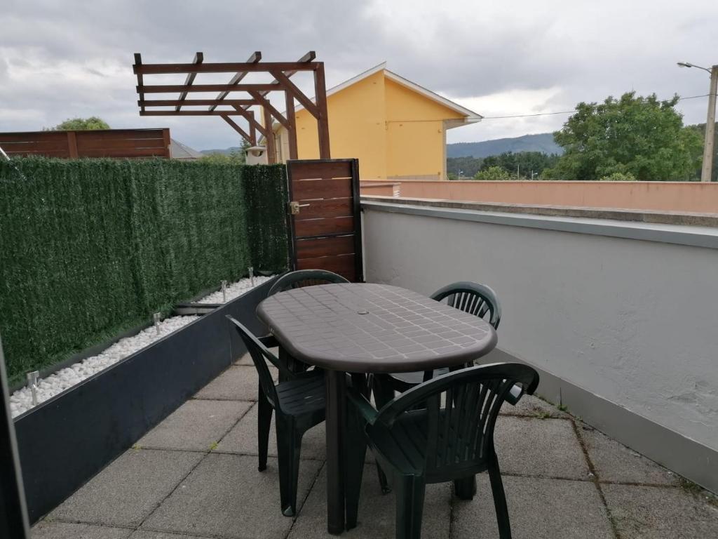 une table et des chaises assises sur une terrasse dans l'établissement Alargos Foz, à Foz