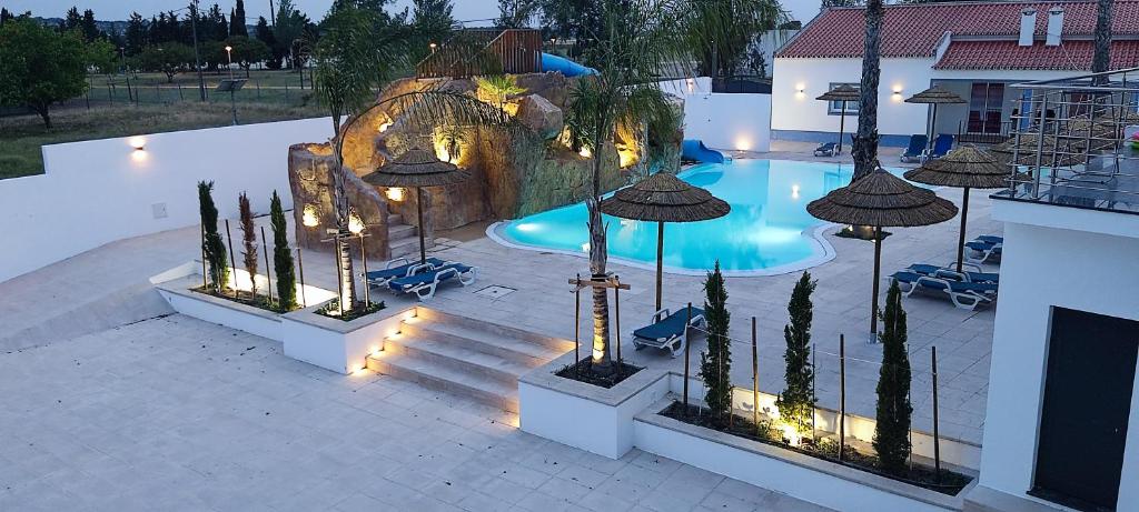 a swimming pool with chairs and umbrellas next to a building at Casa Almeida in Vimieiro