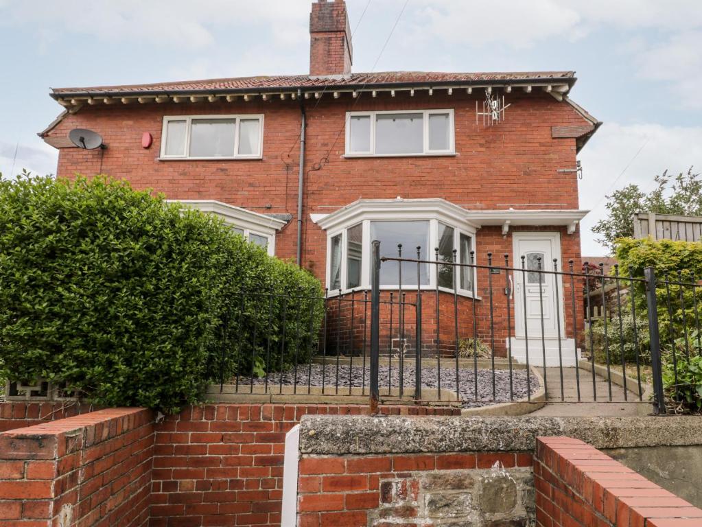 a red brick house with a black fence at Butter Cross in Scarborough
