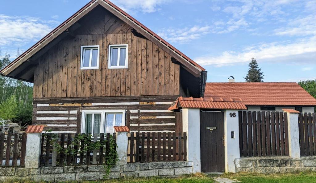 une maison en bois avec une clôture devant elle dans l'établissement Chalupa u rybníka Střehom, à Dolní Bousov