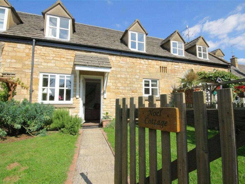 a brick house with a sign on a fence at Noel Cottage in Chipping Campden