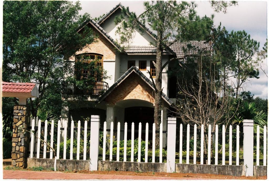 a white picket fence in front of a house at Sum Villa Homestay Mang Den in Kon Von Kla