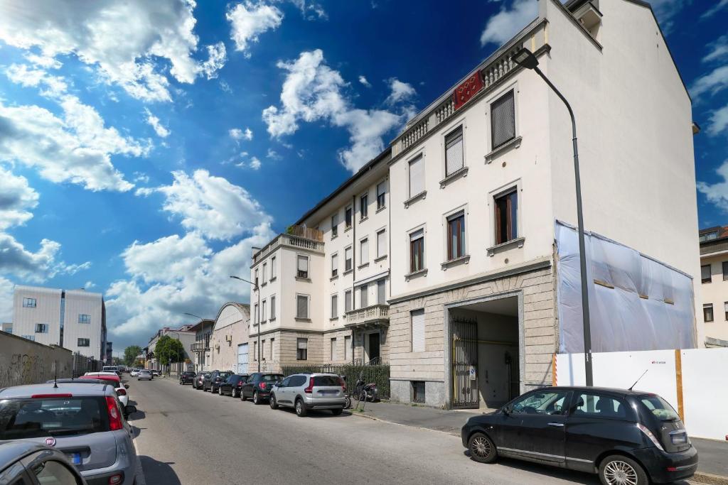biały budynek z samochodami zaparkowanymi po stronie ulicy w obiekcie PrimoPiano - Gargano w Mediolanie