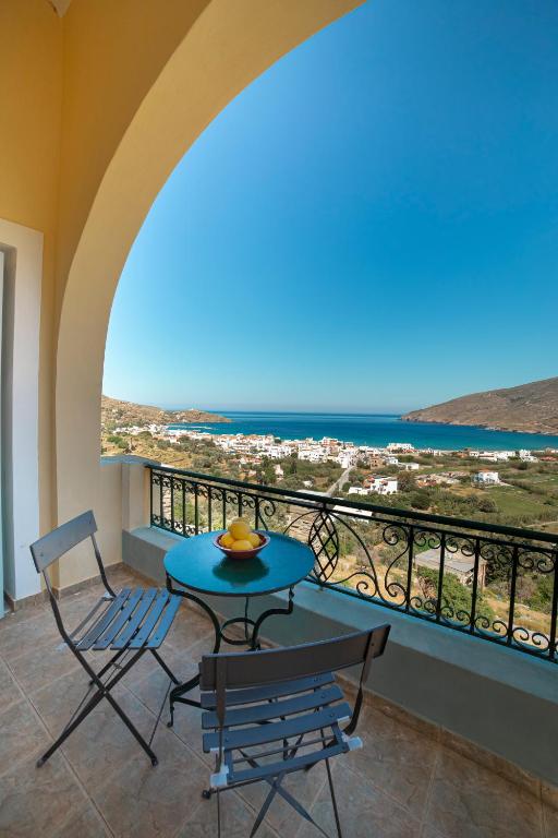 a table and chairs on a balcony with a view of the ocean at Spertos Apartments in Órmos
