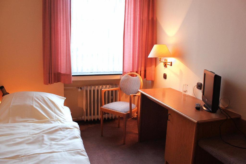 a hotel room with a bed and a desk with a television at Hotel Niederée in Bad Breisig