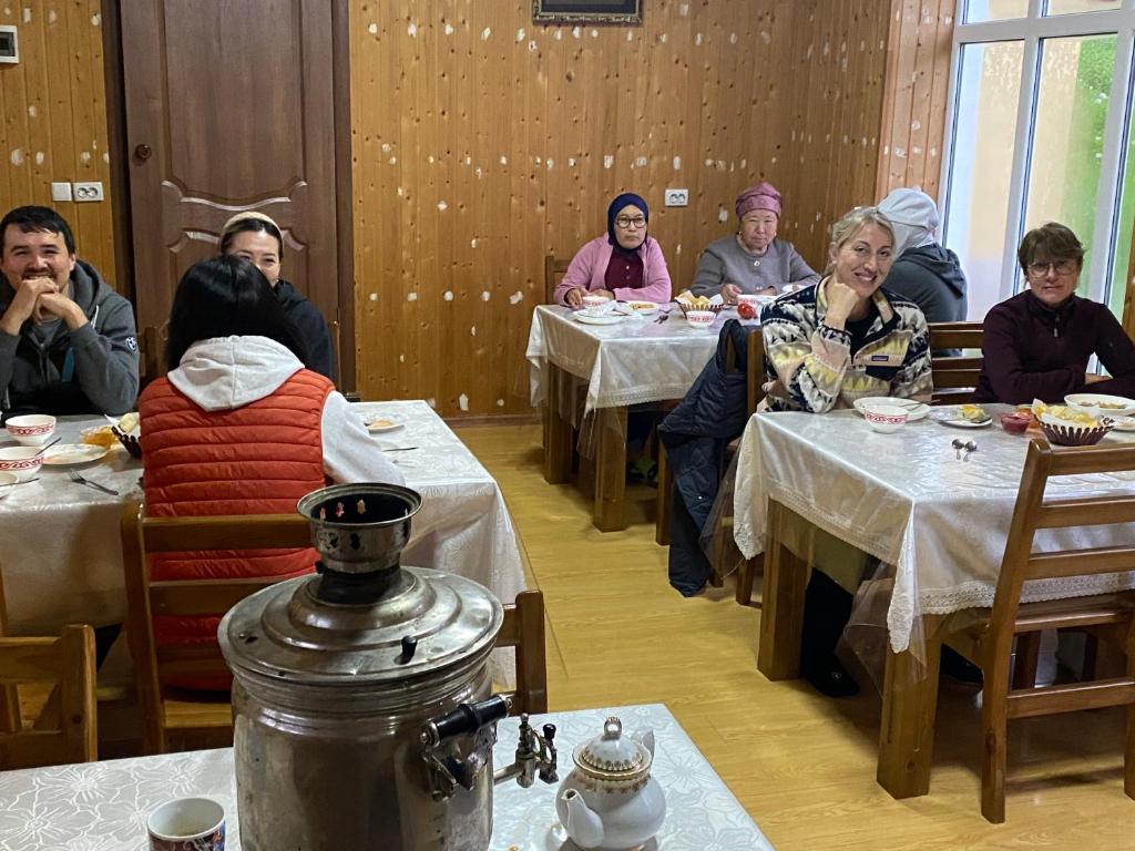 a group of people sitting at tables in a restaurant at Emir in Dzhetyoguz