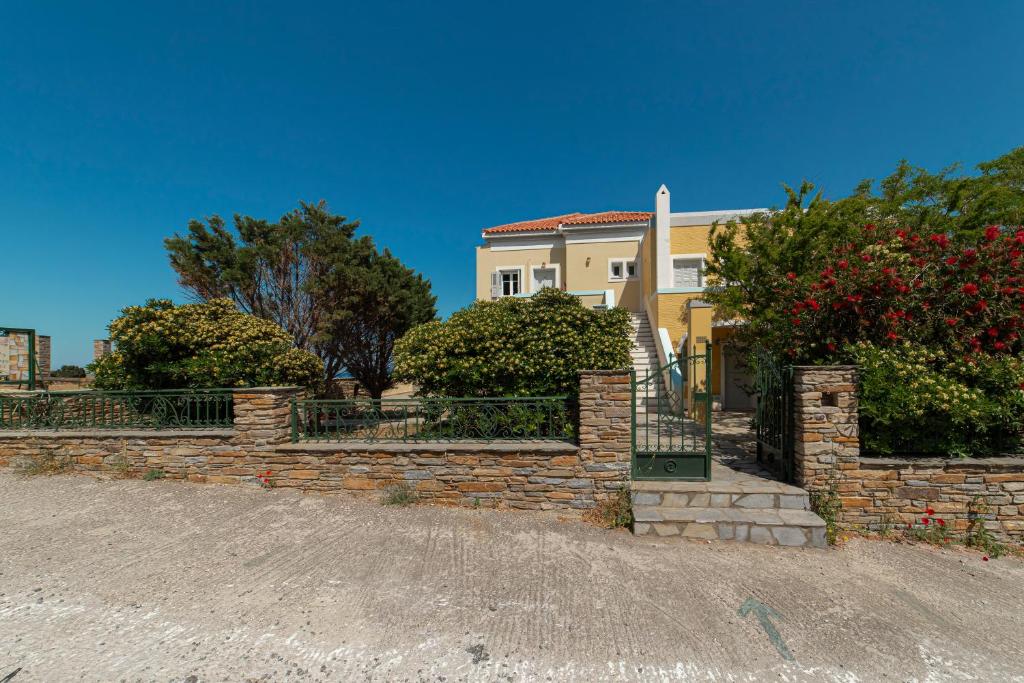 a house with a brick retaining wall and trees at Spertos Apartments in Órmos