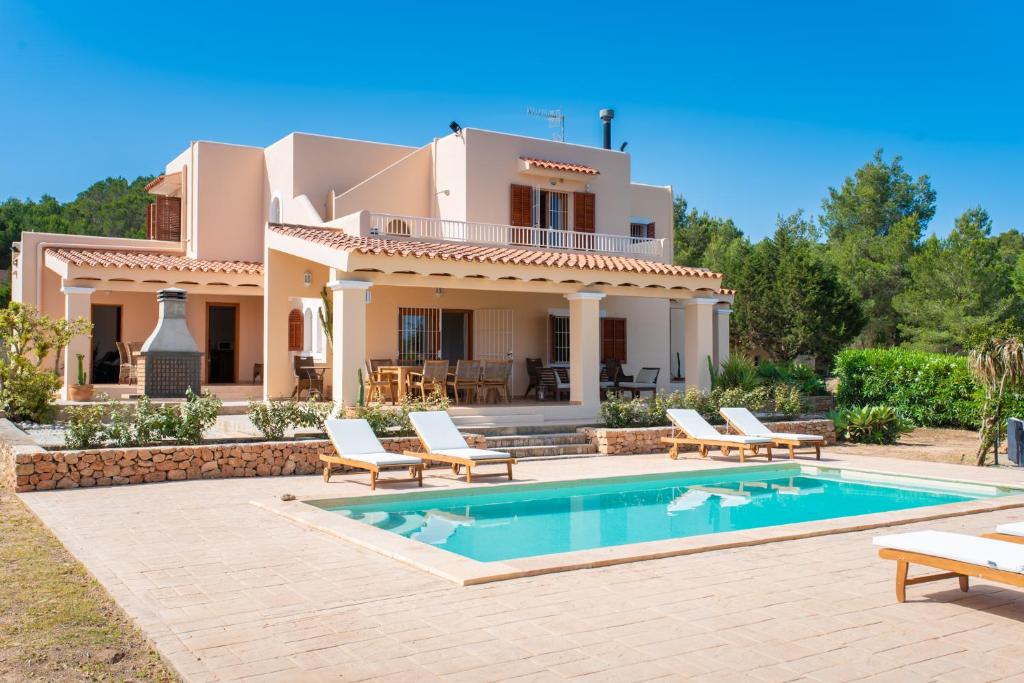 a villa with a swimming pool in front of a house at Can Toni in Sant Josep de sa Talaia