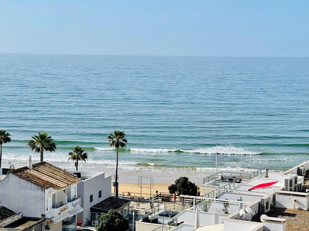 uma vista para uma praia com palmeiras e edifícios em On The BEACH Stunning Apartment Albufeira Olhos de Água em Albufeira