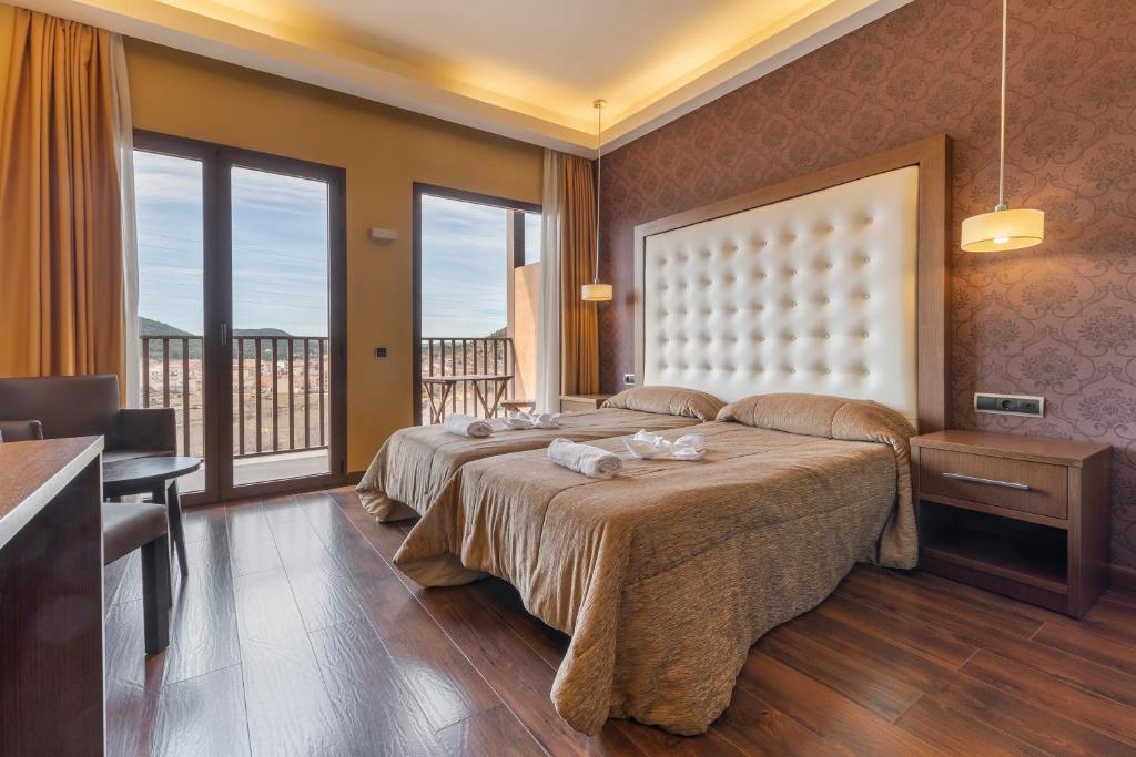 a hotel room with two beds and a balcony at Fuente del Miro in Valderrobres