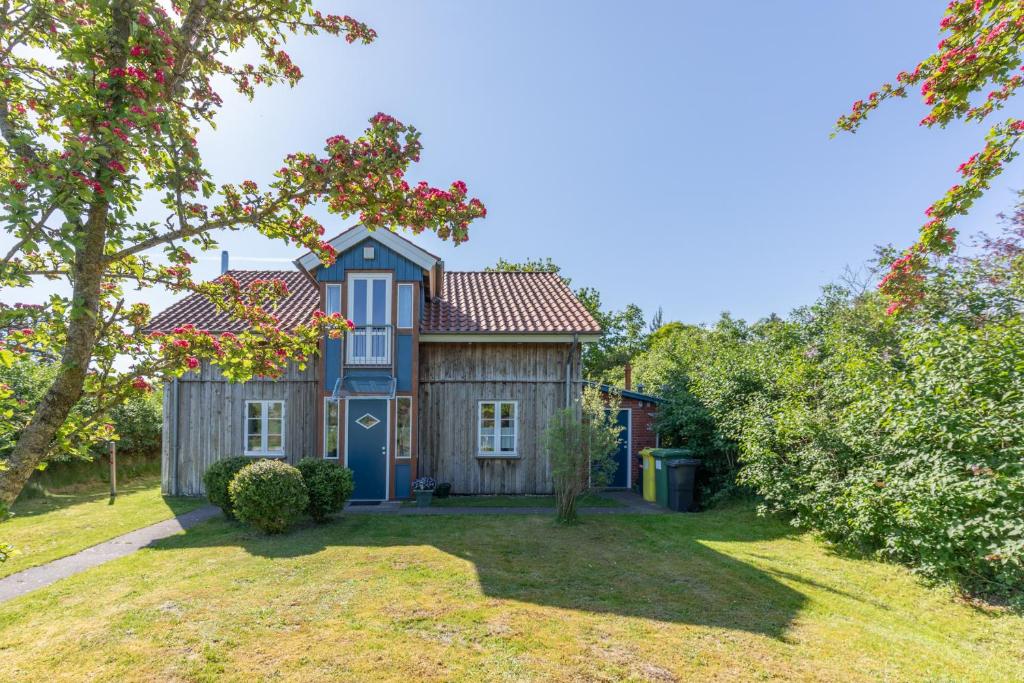 een huis met een blauwe deur in een tuin bij Lütt Huus an de Geestkant in Langenhorn