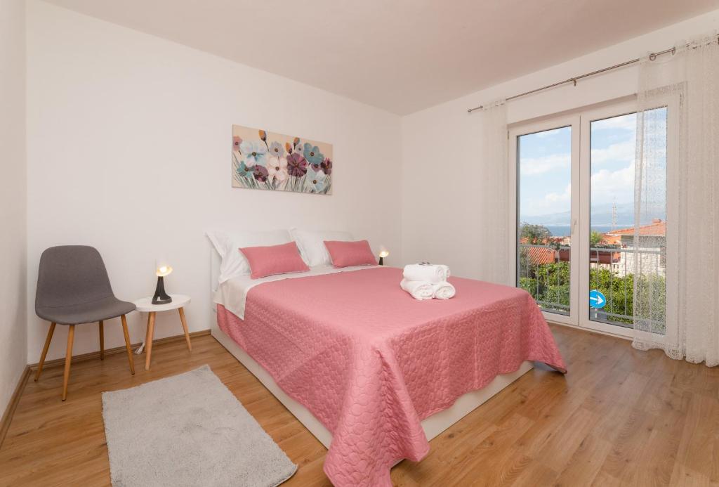 ein Schlafzimmer mit einem Bett mit einer rosa Decke und einem Fenster in der Unterkunft Apartment Nona - Center, 150 meters from the beach in Supetar
