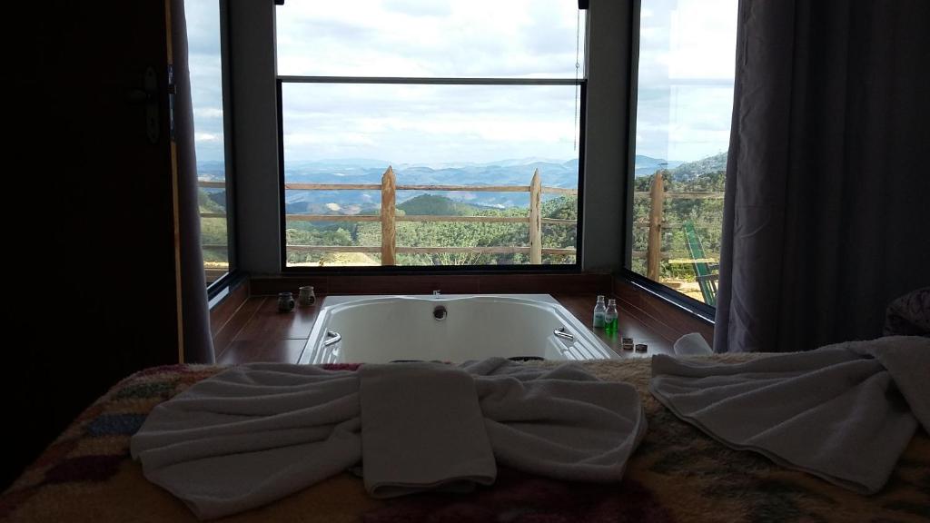 Bett mit Badewanne in einem Zimmer mit Fenster in der Unterkunft Chalé Privilégio in Rio Prêto