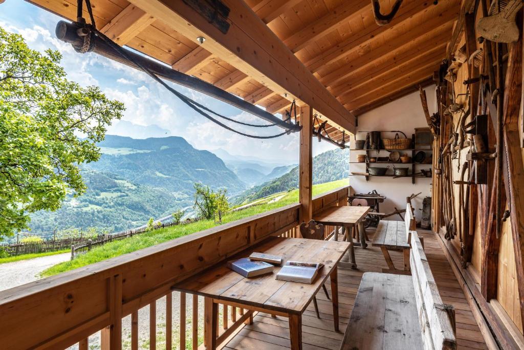 balcón con mesas de madera y vistas a las montañas en App Dolomiten Winklerhof, en Villandro