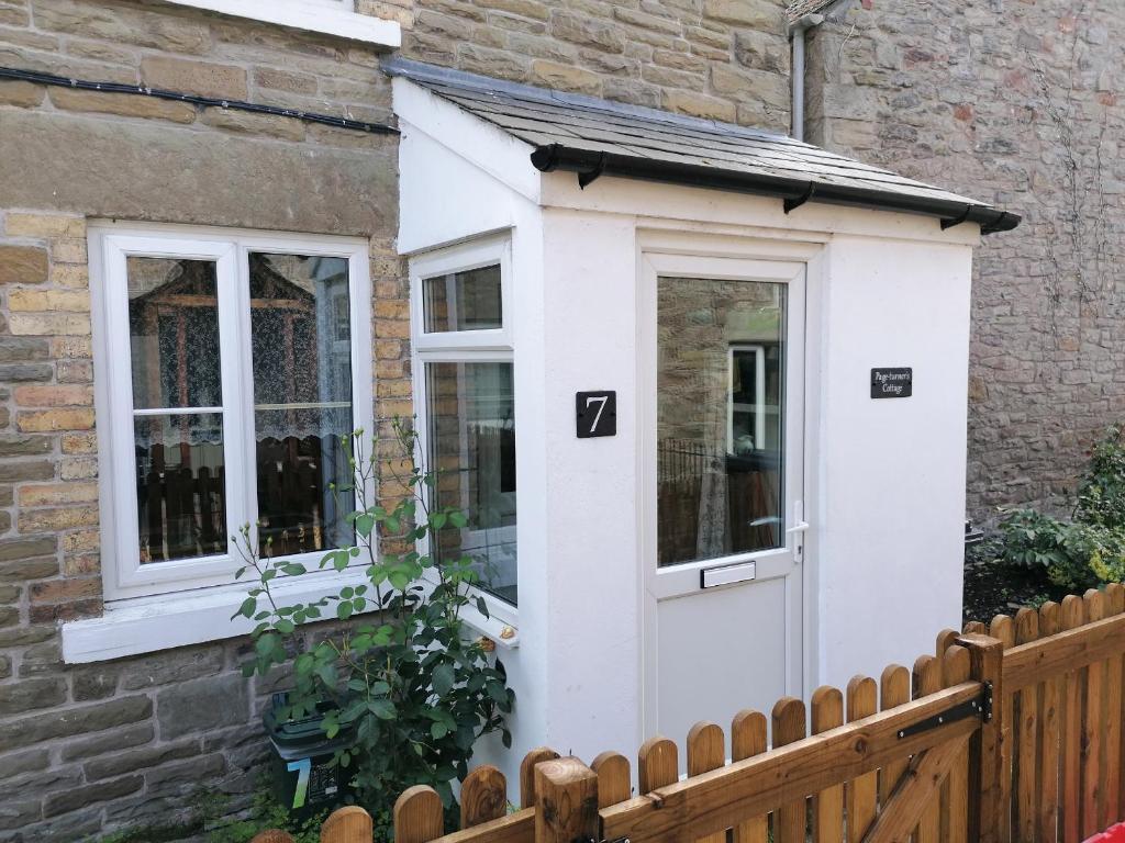 una pequeña puerta blanca en una casa con una valla en Page-turner's Cottage en Hereford