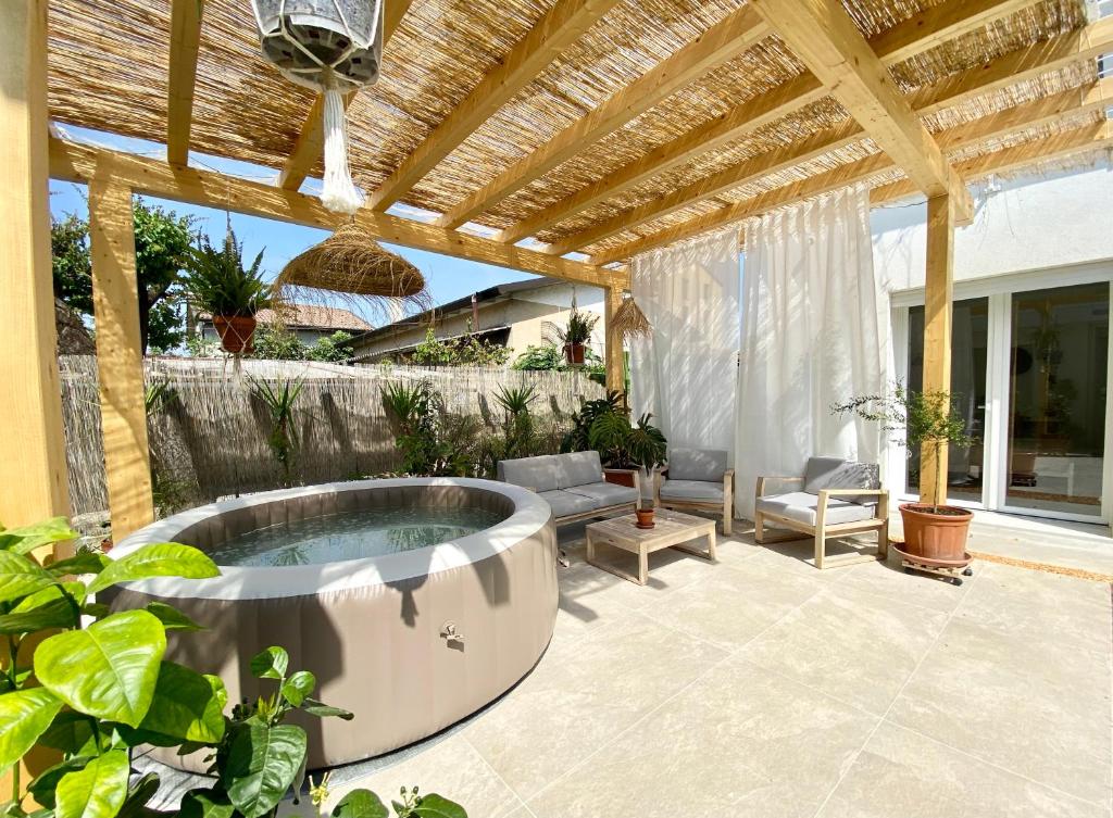 um pátio com uma banheira de hidromassagem sob uma pérgola em Pathos Guest House em Quarto dʼAltino