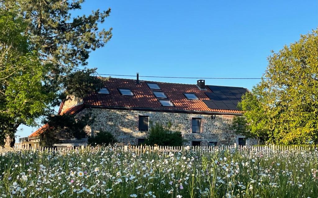 een oud stenen huis met een bloemenveld bij La Souricière in Silenrieux