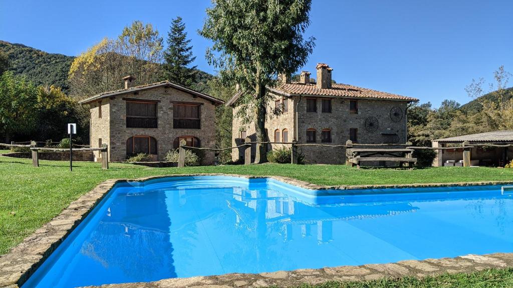 una gran piscina azul frente a una casa en Mas El Carrer en Santa Pau