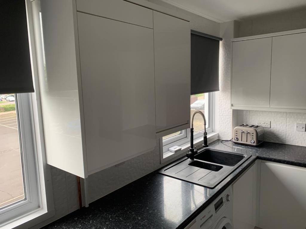 a kitchen with white cabinets and a sink and a window at Double room with private bathroom in Basingstoke in Basingstoke