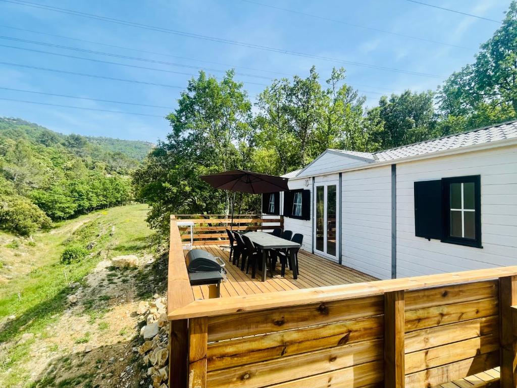 une terrasse en bois avec une table et des chaises dessus dans l'établissement Charmant Chalet avec terrasse et accès piscine., à Rocbaron