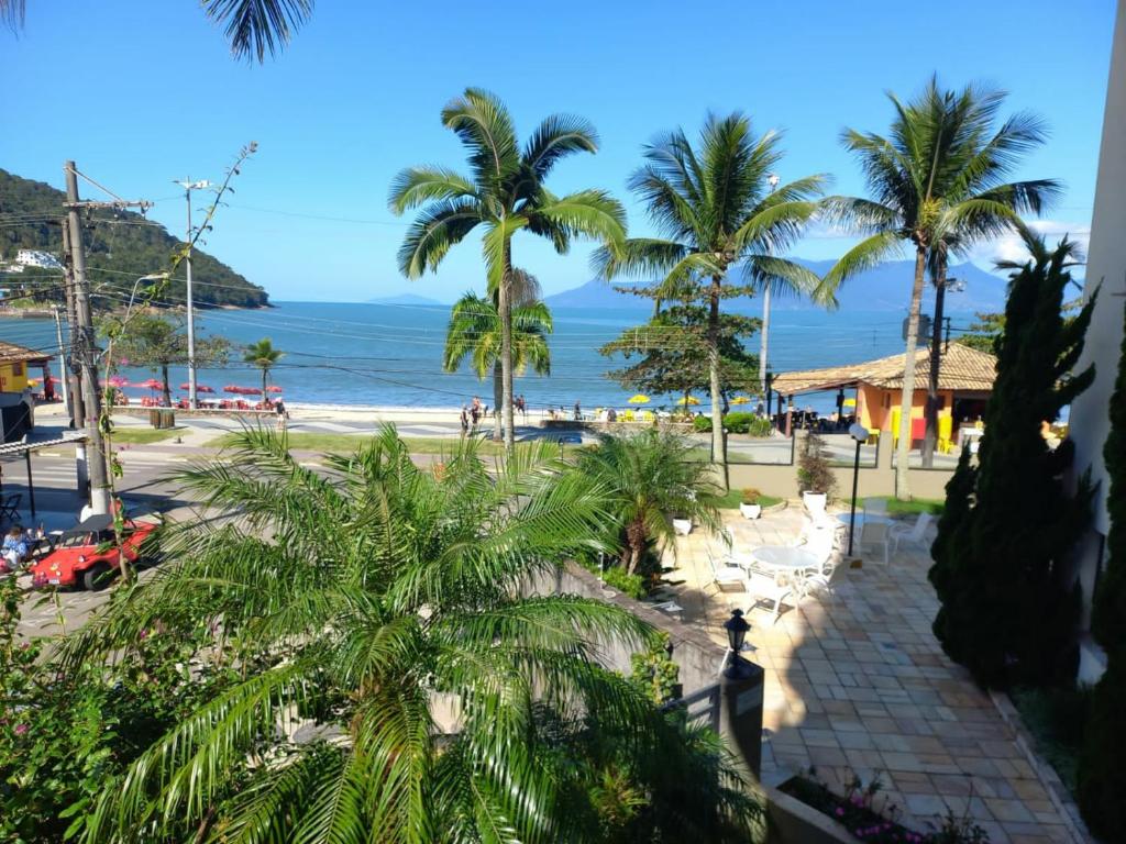 - une vue sur la plage bordée de palmiers et l'océan dans l'établissement Lindo apartamento com vista para o mar em Caraguá!, à Caraguatatuba