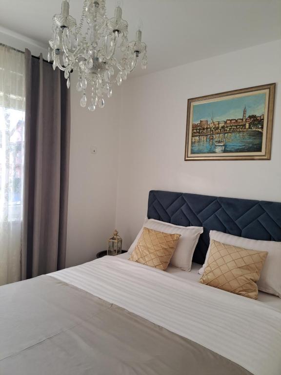 - une chambre avec un grand lit et un lustre dans l'établissement Apartman Stella Maris, à Ljubuški
