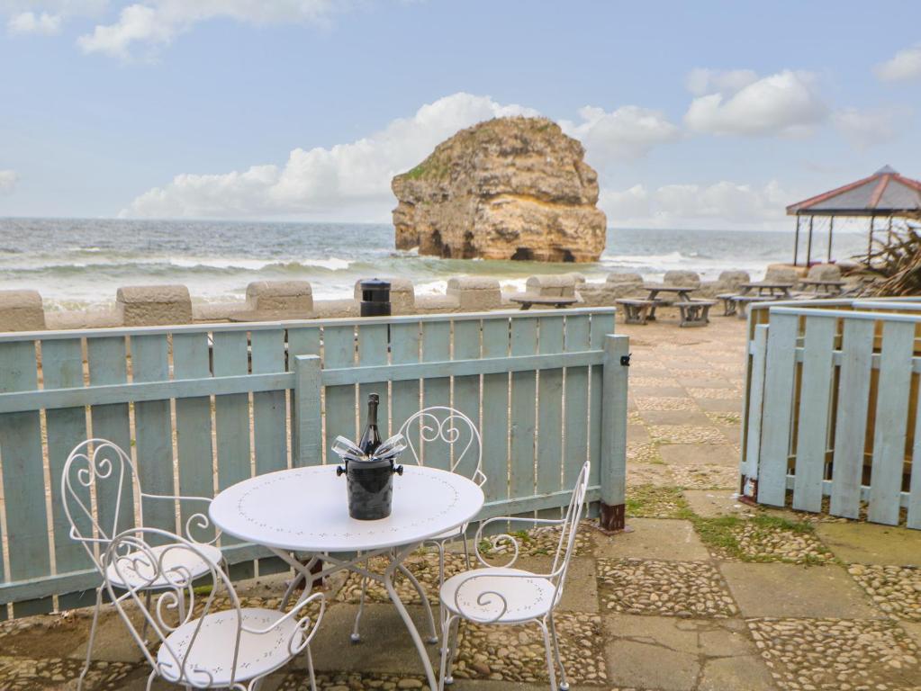 a white table and chairs with a view of the ocean at The Beach Apartment in South Shields