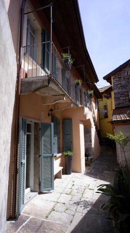 een steeg met een gebouw met groene deuren en een balkon bij La Dimora nel Borgo in Ghiffa