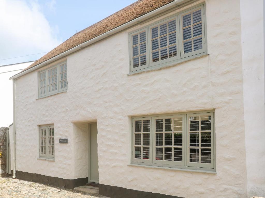 a white house withcolonial windows and gray shutters at Penhale Cottage in Marazion