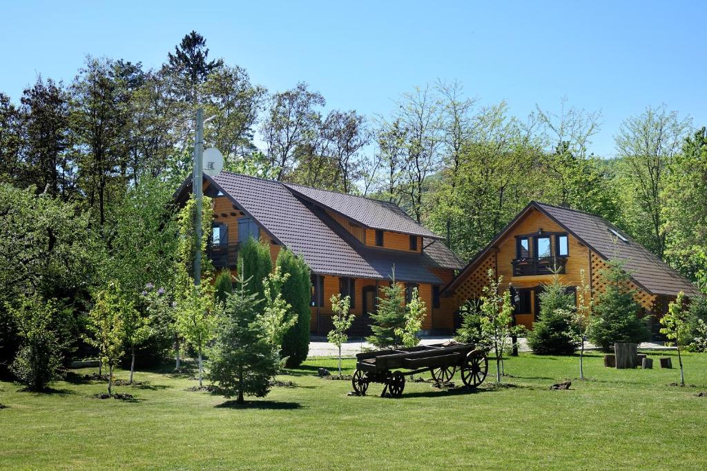 Una casa grande con dos caballos delante. en Cabana Paradisul Verde Neamt en Tîrgu Neamţ