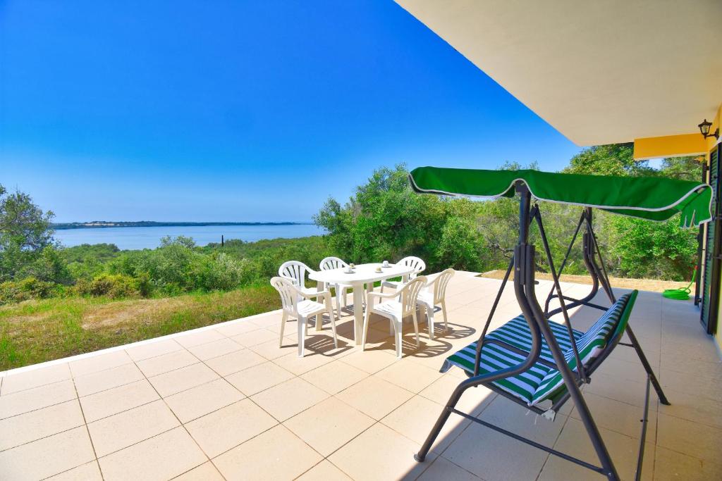 patio ze stołem i krzesłami oraz oceanem w obiekcie Villa Menethea Sea View - 5min from Issos beach w mieście Línia