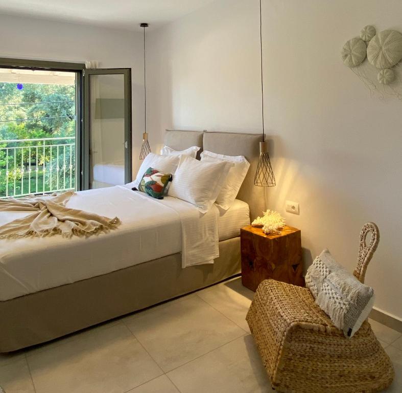 a bedroom with a bed and a chair and a window at OLEA Luxury Apartments in Parga