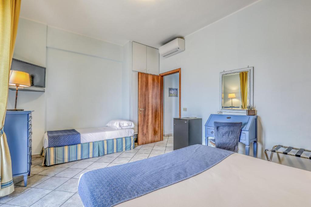 a bedroom with two beds and a mirror at Hotel Albatros Varigotti in Varigotti