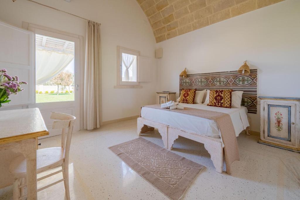een slaapkamer met een bed, een tafel en een raam bij Tenuta Puloni in Otranto