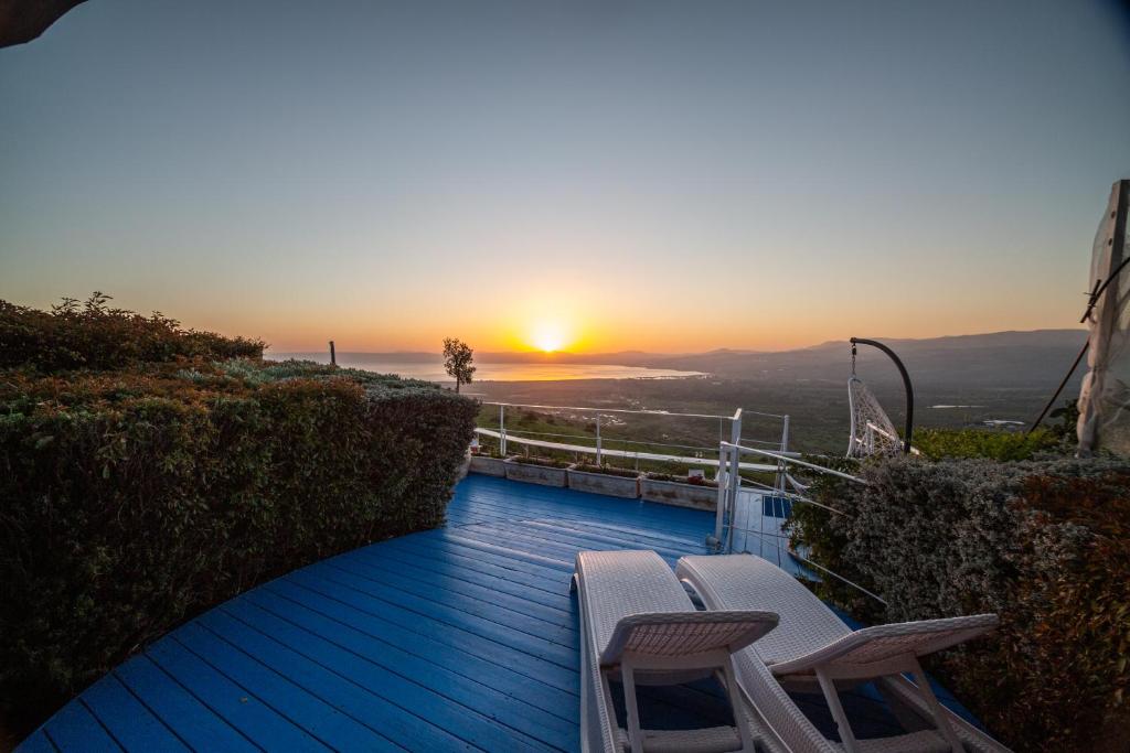 a deck with chairs and a sunset in the background at Sea Zen Resort in Ma'ale Gamla