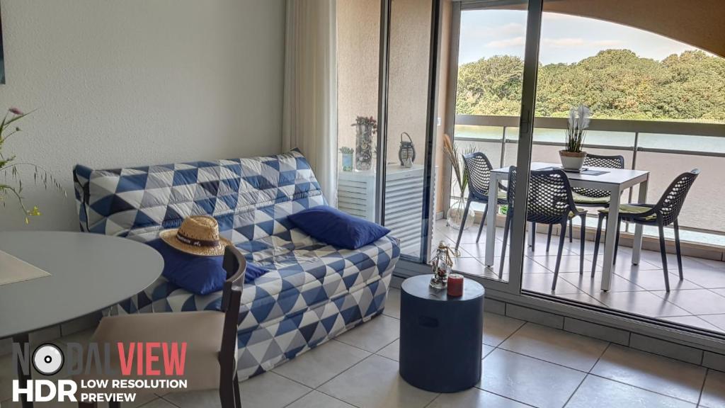 a living room with a couch and a table and a balcony at Quai de la lagune - vue sur la Marina in Saint-Cyprien