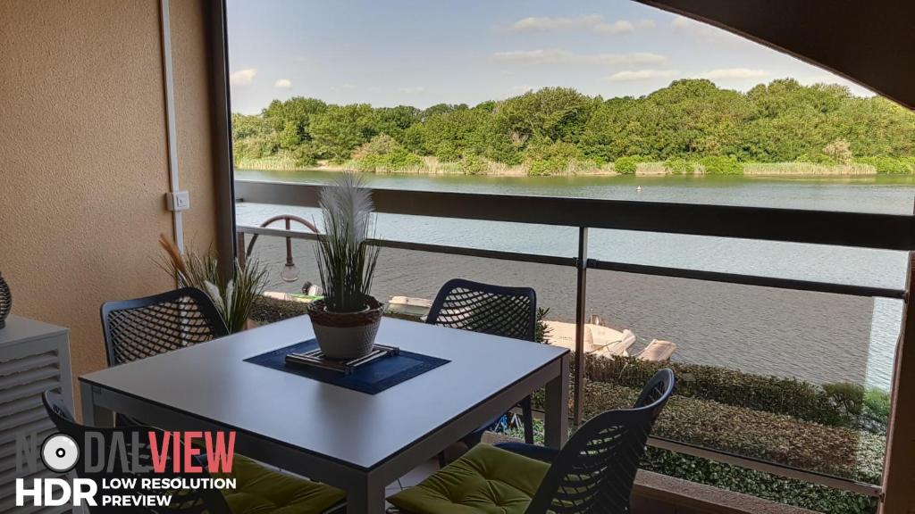 une table sur un balcon avec vue sur l'eau dans l'établissement Quai de la lagune - vue sur la Marina, à Saint-Cyprien