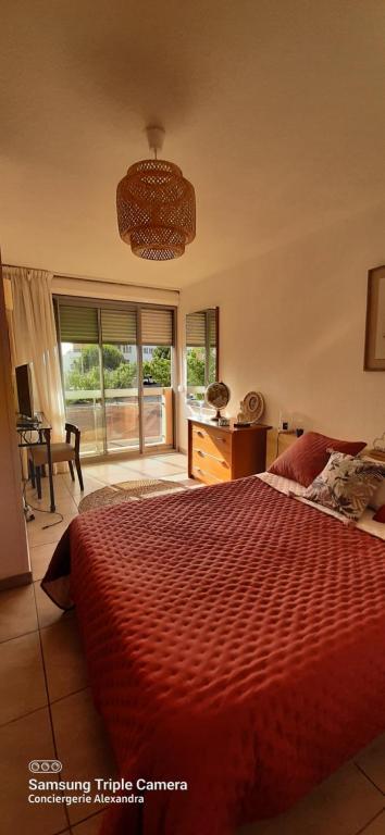 a bedroom with a red bed and a desk and window at Quai de la lagune - vue sur la Marina in Saint-Cyprien