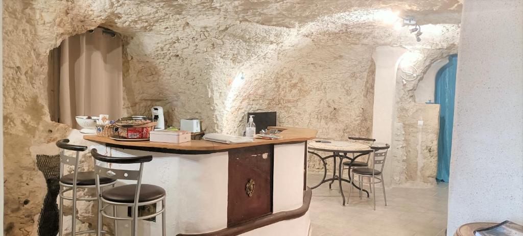 un bar en una habitación con paredes de piedra y taburetes en Cave du Coteau 2, en Lunay