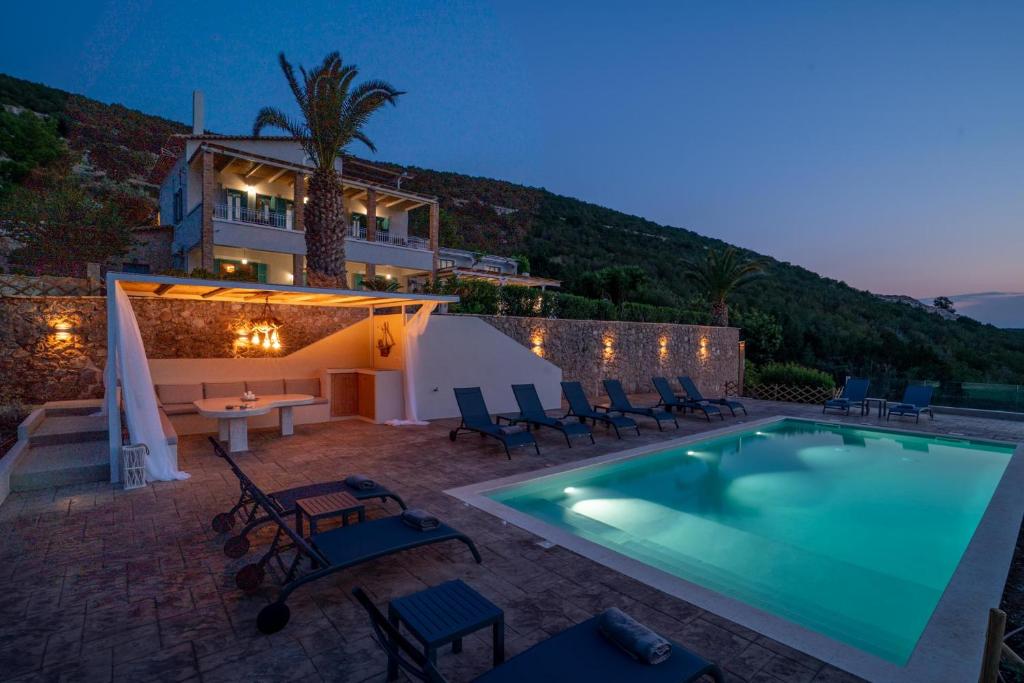 a swimming pool with chairs and a house in the background at Villa Pasiphae in Kranidi