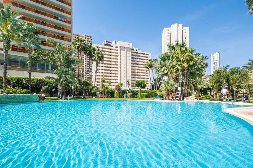 貝尼多姆的住宿－Gemelos 22 Resort Apartment 3-18-B Levante Beach，一座棕榈树和建筑的大型游泳池