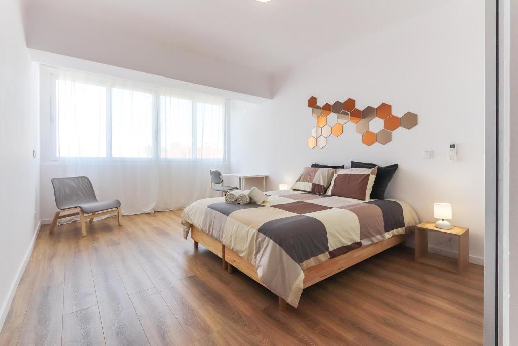 een witte slaapkamer met een groot bed en een stoel bij Vita Portucale ! Costa da Caparica Sunny Design Apartment in Costa da Caparica