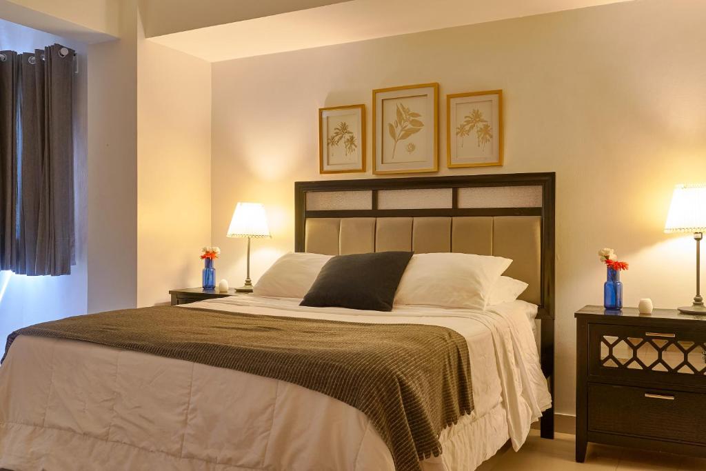 a bedroom with a large bed with two lamps at Apartamento 2BR- AC- WiFi- Safe - Smart TV- HotWater. in Santo Domingo